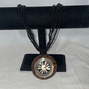 Black beaded necklace with a wooden and shell emblem